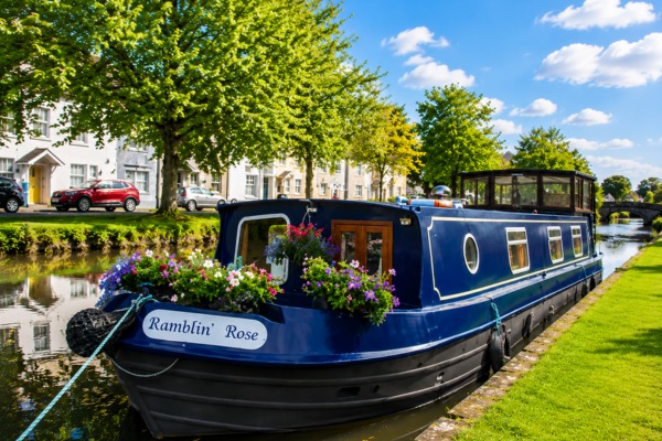 Ramblin Rose canal barge with colourful flower displays moored beside lush green trees in Monasterevin Ireland